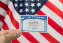 Hand holding social security card, American flag background.