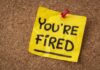 Mass Layoffs? Starbucks Cuts Hundreds! A yellow sticky note pinned to a corkboard with the words 'YOU'RE FIRED' written on it