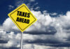 Bezos’s Tax Plan Dazzles – Can It Happen? Yellow road sign reading taxes ahead clouds background