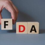 FDA Issues Alert: Pet Food Threat! A hand holding a wooden block with the letter F, next to blocks spelling FDA