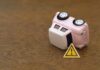 First-Ever Loss Sinking Car Company – $9 Billion EV Blow Upside down pink toy car next to a warning sign