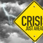 Yellow sign reading Crisis Just Ahead with stormy sky