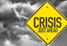 Grocery Crisis: Memorial Day Prices Soar! Yellow sign reading Crisis Just Ahead with stormy sky