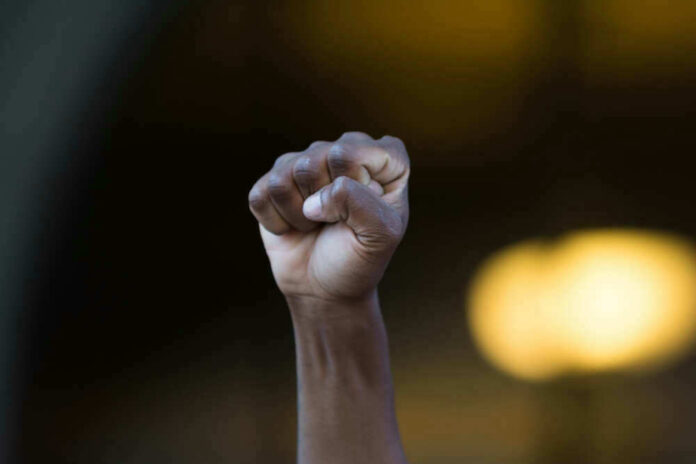 shutterstock_451639279 Raised fist in front of blurred background.