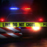 Racist Streamer Faces Attempted Murder Charge Police car with flashing lights behind caution tape.