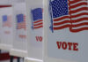 Voting booths with American flags and VOTE signs.