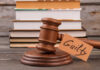 A wooden gavel with a tag reading 'Guilty' next to stacked books