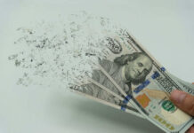 Jobs Boom As Trillions Vanish Hundred-dollar bills disintegrating in hand.