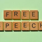 Free Speech Decision Ends Prison Term Wooden letter tiles spelling 'FREE SPEECH' on a light green background