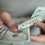 Welder’s Million Dollar Gamble Shocks Co-Workers Hands holding stack of one hundred dollar bills