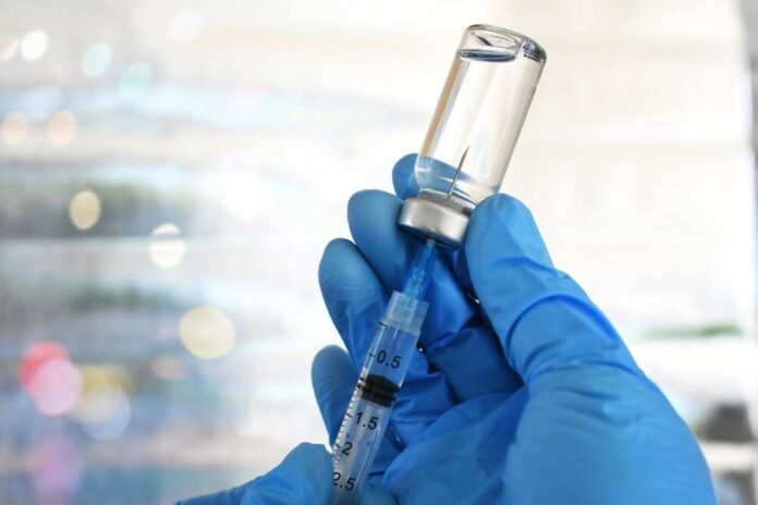 Medical,Personnel,Filling,A,Syringe,Needle,With,Generic,Vaccine,Booster A gloved hand holding a syringe and a vial of liquid