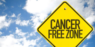 A yellow warning sign that reads 'CANCER FREE ZONE' against a blue sky