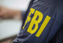 FBI’s Most Wanted Fraudster Targeted Kids Person wearing FBI jacket, letters in yellow.