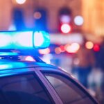 Holiday Massacre – 12 Victims Close-up of a police car with blue emergency lights in a city at night