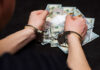 Deli Stock Hits $100M — Then Handcuffs Person in handcuffs surrounded by cash