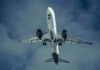 Midair Stench Triggers Emergency Landing Airplane flying in cloudy sky, underbelly view.