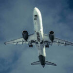 Airplane flying in cloudy sky, underbelly view.