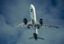 Midair Stench Triggers Emergency Landing Airplane flying in cloudy sky, underbelly view.