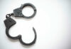 Infamous Athlete In Handcuffs — Now What? Open metal handcuffs on white background.