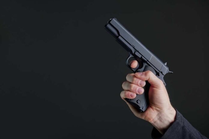 Male,Hand,Holding,A,Gun,On,Black,Background,.,A