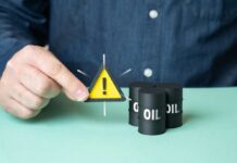 A person holding a warning sign next to oil barrels