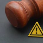 Trump Pardon Backfires: Judge Drops Hammer Wooden gavel with a yellow warning triangle sign on dark surface