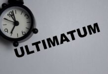 A black alarm clock next to the word 'ULTIMATUM' on a gray background