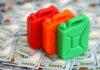 Gas Jump Signals Bigger Shock Three colorful plastic containers on a background of hundred dollar bills