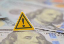 White House Aide’s $100K Crime Revealed? A warning sign placed on top of U.S. dollar bills