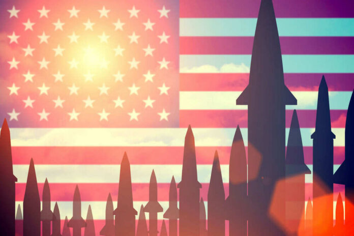 shutterstock_405618091 Missiles silhouetted against American flag background with sunset.
