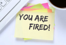 Pregnant, Then Pink-Slipped? A sticky note with the message 'YOU ARE FIRED!' placed on a desk next to a keyboard and a cup of coffee