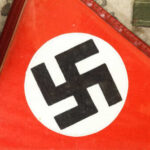 Hitler’s Lost Fleet Resurfaces — Loaded With Explosives Close-up of a red flag featuring a black swastika symbol