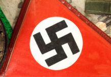 Hitler’s Lost Fleet Resurfaces — Loaded With Explosives Close-up of a red flag featuring a black swastika symbol