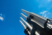 Missiles silhouetted against American flag background with sunset.