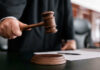 Damages Cap Guts Alex Jones Payout Judge holding gavel in courtroom.