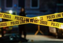 She’s DEAD – Manhunt Ends With Twist Police tape marking a crime scene with blurred figures in the background