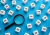 Magnifying glass among cubes labeled job on blue background