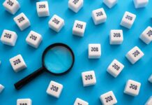 Magnifying glass among cubes labeled job on blue background