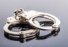 Close-up of metallic handcuffs on a reflective surface