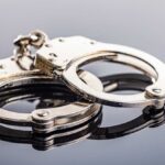 Close-up of metallic handcuffs on a reflective surface