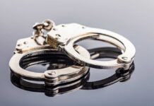 Close-up of metallic handcuffs on a reflective surface
