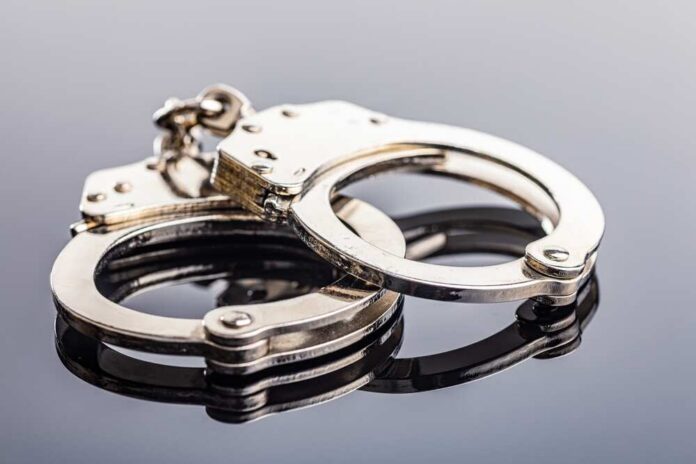 Shiny,Metal,Handcuffs,On,The,Mirror,Table. Close-up of metallic handcuffs on a reflective surface