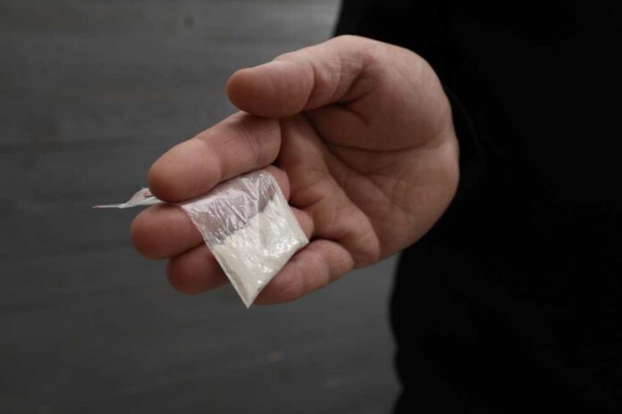 Drug,Addiction.,Man,With,Plastic,Bag,Of,Cocaine,On,Grey