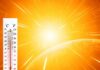 Thermometer displaying high temperature against a bright sun