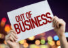 Hands holding an out of business sign