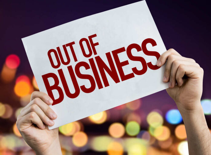 Out,Of,Business,Placard,With,Night,Lights,On,Background Hands holding an out of business sign