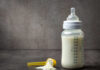 NOW: Whole Milk Shocker Announced A baby bottle filled with milk next to a scoop of powdered formula