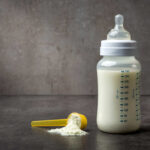 NOW: Whole Milk Shocker Announced A baby bottle filled with milk next to a scoop of powdered formula
