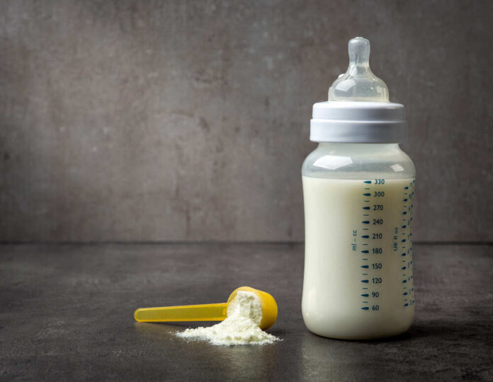 Bottle,Of,Baby,Milk,On,Dark,Grey,Table A baby bottle filled with milk next to a scoop of powdered formula