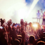 Star Power, Real Lives In Need Concert crowd with hands raised, bright stage lights.